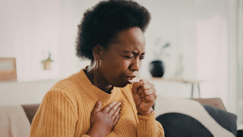 Person coughing at home, illustrating respiratory symptoms that may occur with mold exposure and concerns about whether black mold is dangerous.